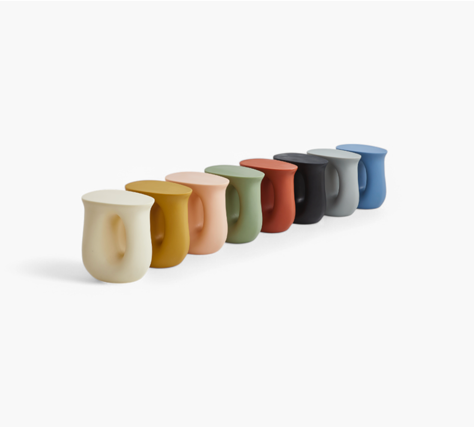 Collection of colorful accent furniture stools in various muted tones arranged in a row on a white background