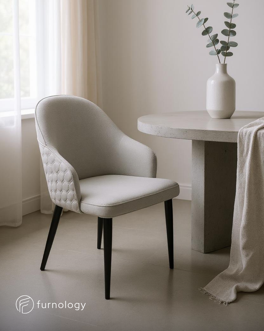 Modern upholstered dining chairs with quilted back and black legs next to a round dining table in a bright room