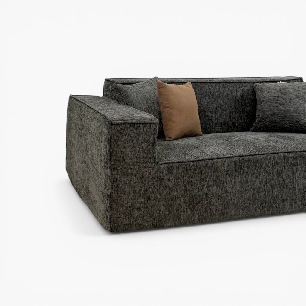 Furnology Blocco Compressed 3 seater sofa in dark grey textured fabric with a single brown accent pillow.